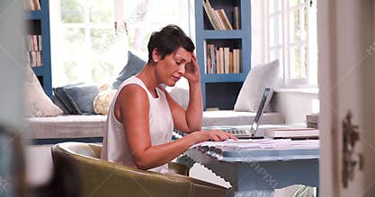 Mature Woman At Desk Working In Home Office With Laptop