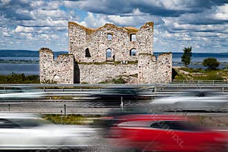 Modern speedy cars and an old ruin