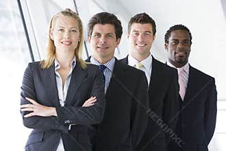 Four businesspeople standing in corridor smiling