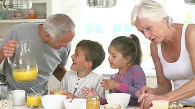 Grandparents With Grandchildren Making Breakfast In Kitchen