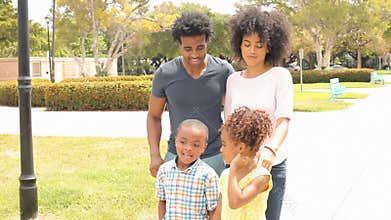 Parents Walking With Children In Park