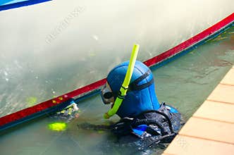 Diver cleaning boat hull maintenance work at dock