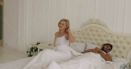 Couple sleep lying on bed morning wake up happy smile man hug woman home white bedroom