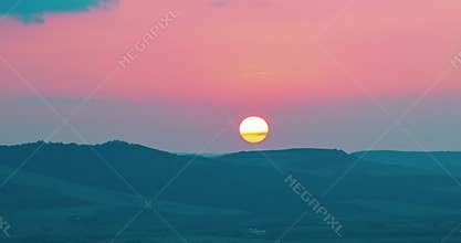 Sunset scene with sun fall behind the violet clouds in background, time lapse shot, warm colorful sky