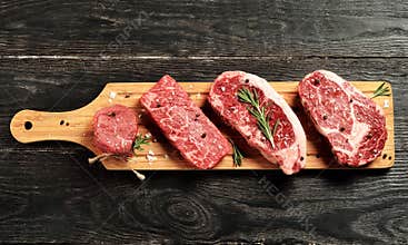 Fresh raw Prime Black Angus beef steaks on wooden board