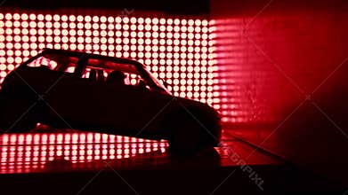 Toy car crashing into wall. Crash test lab concept. Red lights background, super slow motion video