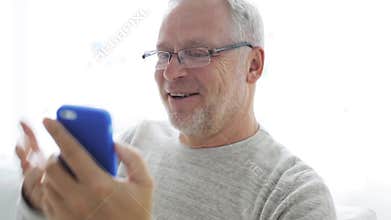 Senior man having video call on smartphone at home 126