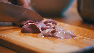 Woman Chef Slices Chicken Liver Meat on a Wooden Kitchen Board in Home Kitchen.