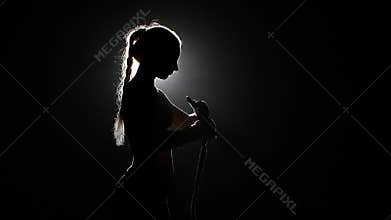 Boxer shakes special bandages on his hands. Silhouette. Black background . Side view. Close up. Slow motion
