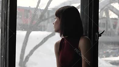 Beautiful sad girl by the window at home