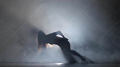 Performed sports girl in dark studio booty dance in silhouette