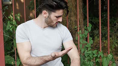 Young man getting stung by mosquito outdoor
