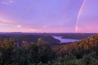 A Purple Colored Sky with a Rainbow at Sunset over Mountain Lake