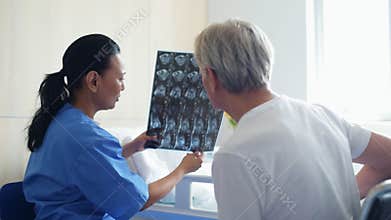 Nice female doctor discussing xray scan with a senior man