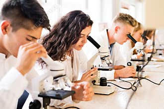Beautiful high school students with microscopes in laboratory.