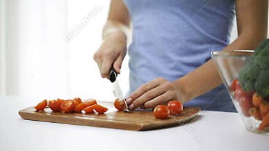 Close up of young woman chopping tomatoes at home