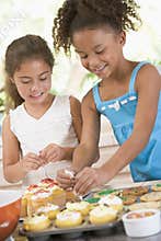 Two children in kitchen decorating cookies