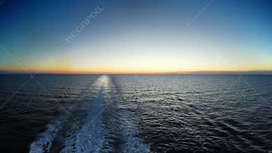 Water trace behind boat in sunset
