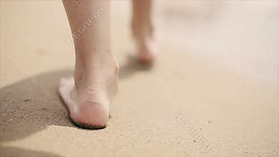 Girl walking barefoot on the beach sand along the sea. Slow motion