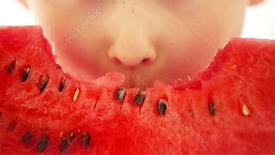 Happy boy appetizing eating red watermelon and juice flowing under the teeth