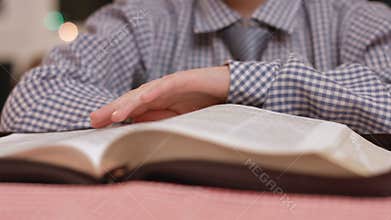 Boy's hand turns book pages.