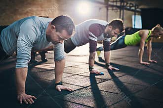 Three adults performing push up exercises