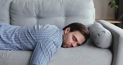 Exhausted man came home after work flopped down on sofa