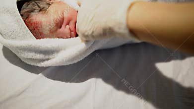 Asian Chinese baby being wrapped in thick warm blanket after physical examination
