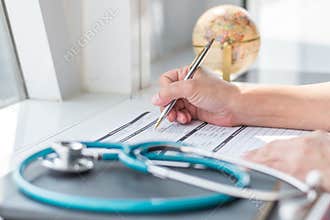 Physician doctor writing on medical health care record, patients discharge, or prescription form paperwork in hospital clinic
