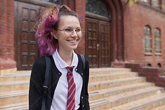 Female student teenager in uniform with backpack, building school background