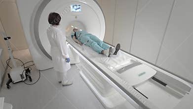 Doctor makes an MRI scan for a patient in a clinic. The girl lies in the MRI device. Magnetic resonance imaging in the