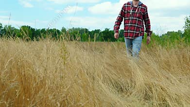 Man in a red jacket walks on the grass in nature in the fall. Hiking and tourism.