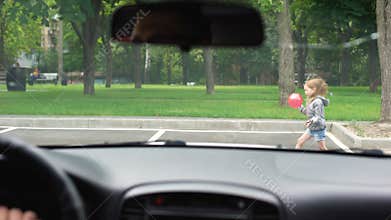 Small girl playing with ball on parking lot, car driver braking sharply, risk