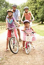 Family Cycling In Countryside Wearing Safety Helme