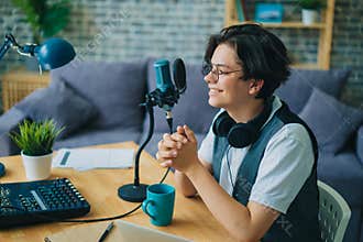 Joyful teen speaking in microphone in studio recording podcast alone