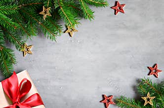 Christmas presents with red ribbon on gray background in a frame made of fir branches with star. Flat lay, top view. Christmas