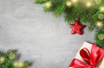 Christmas presents with red ribbon on gray background in a frame made of fir branches with star. Flat lay, top view. Christmas