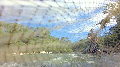 Indigenous man throwing a fishing net in the river