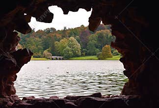 An early Autumn / Fall scene through the stone window of a rustic garden grotto