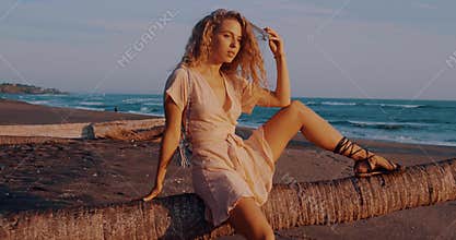 Beautiful girl in dress posing for the photographer on the beach