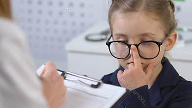 Female child looking at optometrist filling patient card, eyesight examination