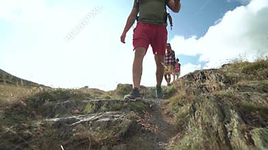 Friends walking along hiking trail path. Group of friends people summer adventure journey in mountain nature outdoors.