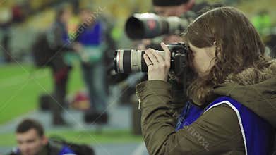 A photographer, photographers with a camera in a stadium during a football match.