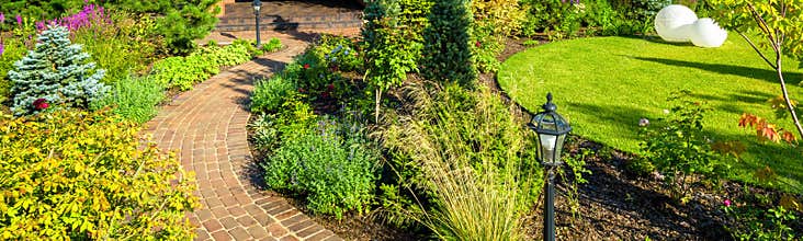Landscaping in nice green garden in summer. Panoramic view of landscaped place at residential house