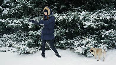 Crazy emotional dance from woman at snowy park, nearby funny pug dog pisses and marks a Christmas tree