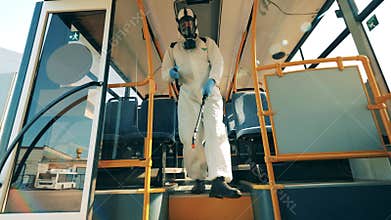 Disinfector is walking along the bus and sanitizing it. Coronavirus prevention, sanitary disinfection process.