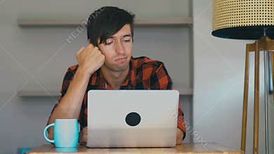 Tired bored freelancer man work at home with laptop