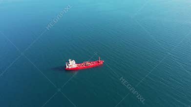 Red oil tanker sails among boundless azure ocean aerial view