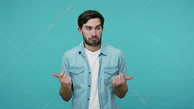 Confused bearded guy in jeans shirt looking at camera with embarrassed expression	 gesturing i don`t know	 have no idea	 being clu