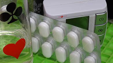the medicine. pills in a blister, a glass of water with card drawings of a heart, a cross. tonometer.